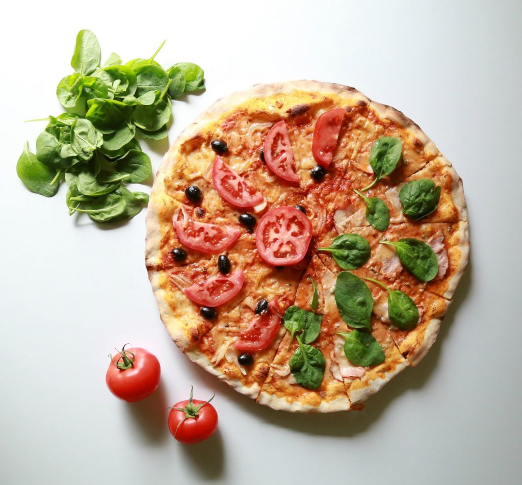 Image of pizza with spinach and tomatoes
