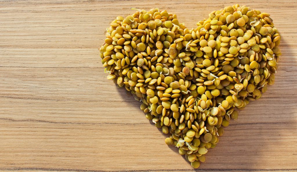 Lentils forming a heart on wood background