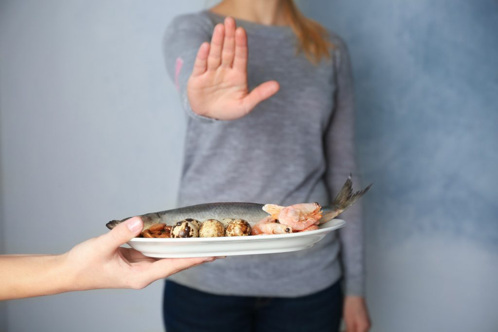 Woman refusing plate full of allergens