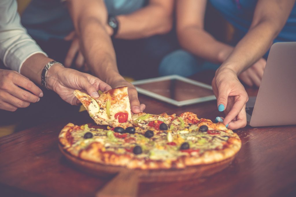 Group of people eating pizza around a table