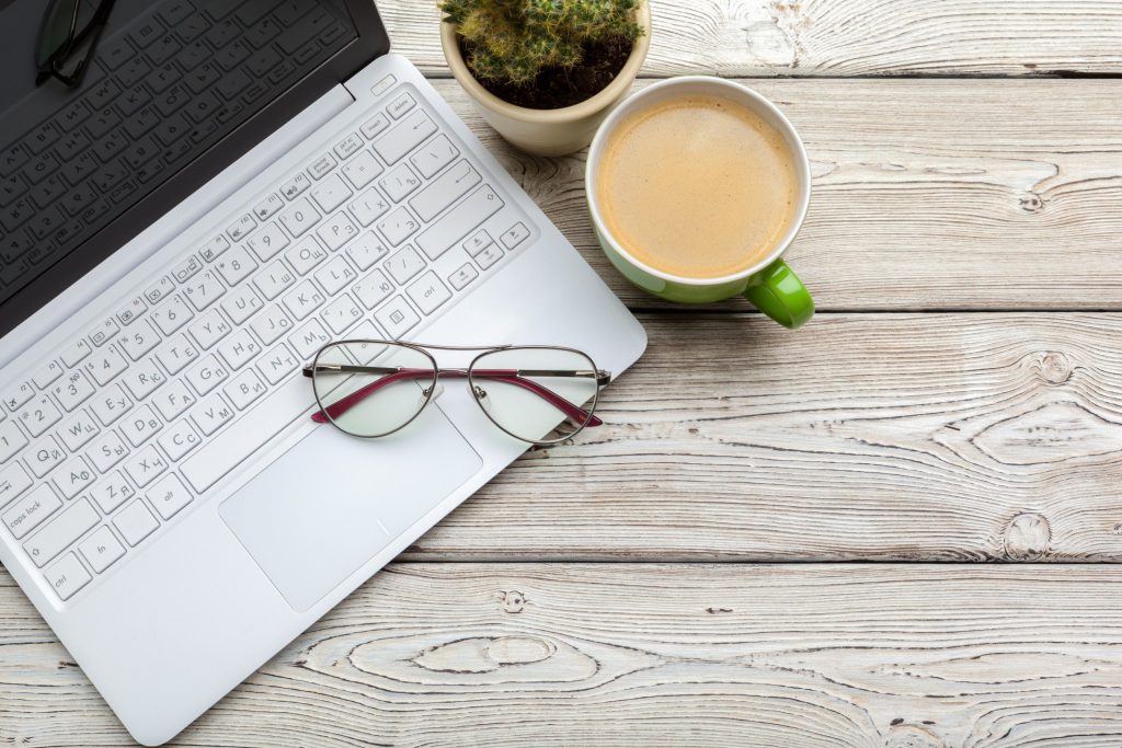 Computer with reading glasses and cup of coffee