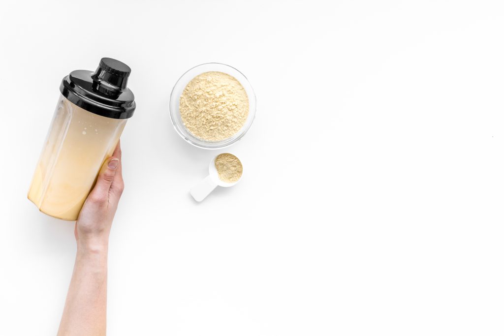 Hand holding supplement shaker near powder