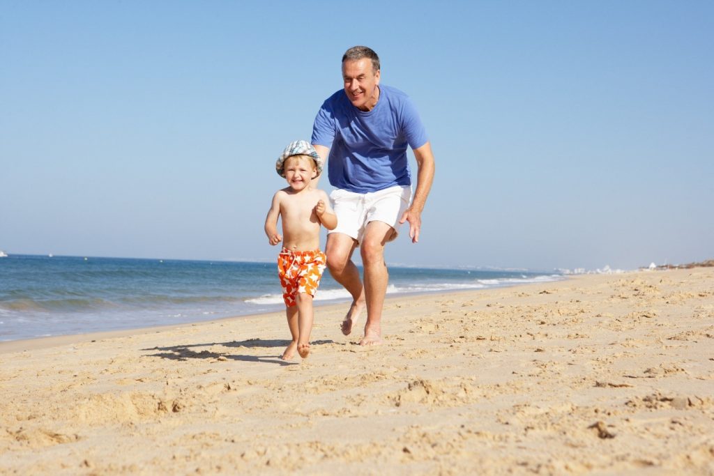 Man running with grandson on beach