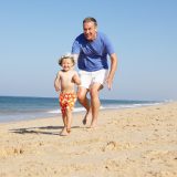 Man running with grandson on beach